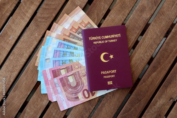Obraz Turkish passport with Euro banknotes on wooden table photographed from above