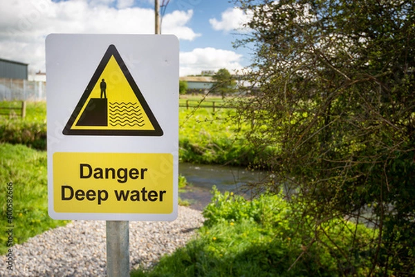 Fototapeta Danger Deep Water warning sign close up by rural waterway river stream. Beware falling in, drowning.