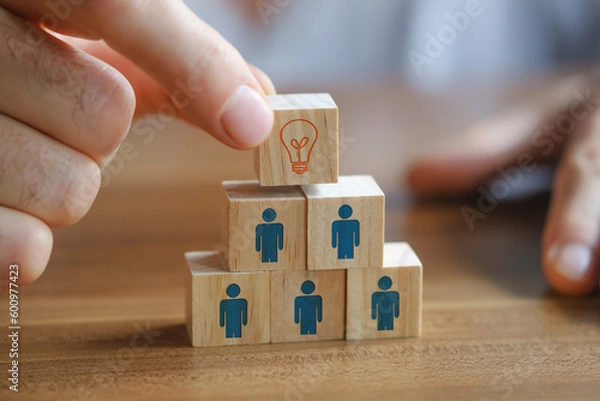 Obraz Man holding a wooden cube with light bulb on it. Teamwork and employment business concept