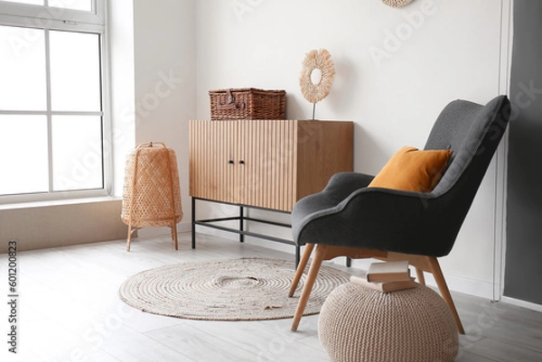 Fototapeta Interior of stylish living room with wooden cabinet and cozy armchair