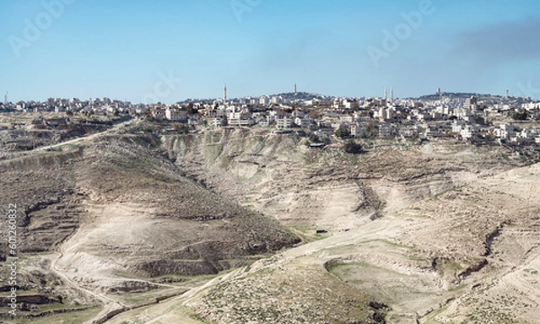 Fototapeta the ancient Palestinian town of al-Azariya sits in front of the towers of East Jerusalem and behind barren desert hills with a blue sky in the background