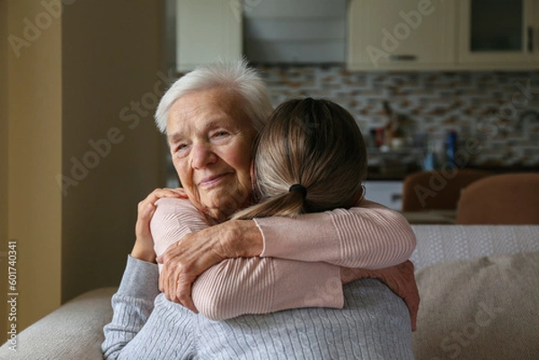 Obraz Grandmother and granddaughter hugging in the living room. Two adult women of different age. Family values concept. Close up, copy space, background.