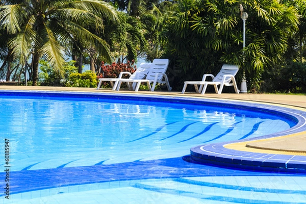 Fototapeta luxury swimming pool with sundeck white close up in tropical gar