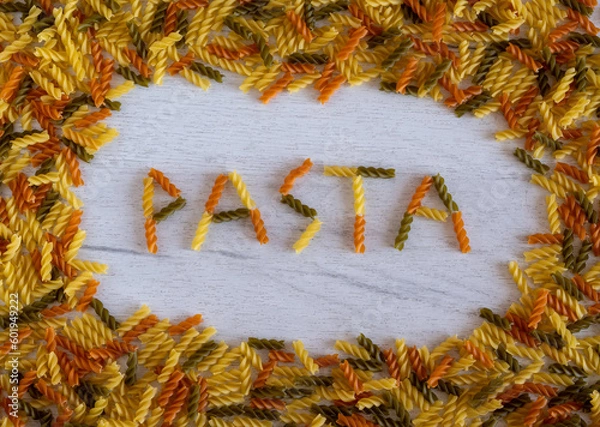 Obraz The word pasta is laid out of fusilli pasta on a white wooden background on pasta frame