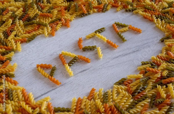 Obraz The word pasta is laid out of fusilli pasta on a white wooden background on pasta frame
