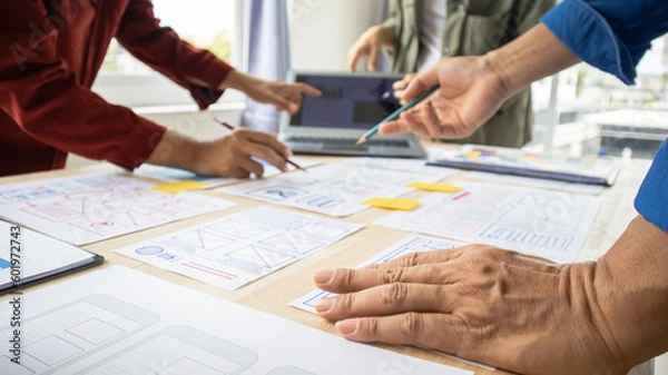 Fototapeta Close-up ux developers and ui designers use augmented reality to brainstorm on mobile app interface wireframe designs on modern office desks. Creative digital development office