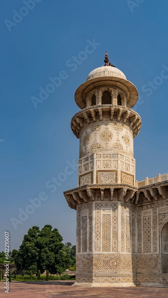Obraz Details of the architecture of the ancient tomb of Itmad-Ud-Daulah. Marble minaret with balconies and a dome against the blue sky. On the walls there are ornaments, inlays of precious stones. India.