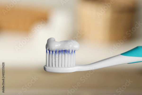 Fototapeta Plastic toothbrush with paste on blurred background, closeup
