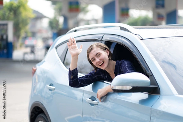 Fototapeta Beautiful White Cuacacian woman say hi to camera while sitting in electrical car ready for her destination in traveling with smile of happiness.