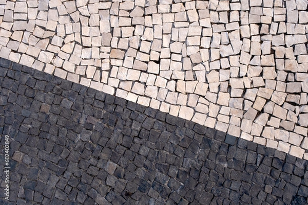 Fototapeta Portuguese traditional black and white pavement made from calcada tiling. Fragment of sidewalk paving in Funchal, Madeira island