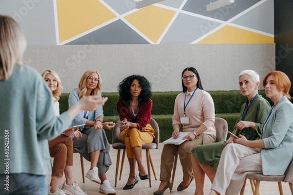 Obraz Group of confident mature women listening to speaker while visiting business conference