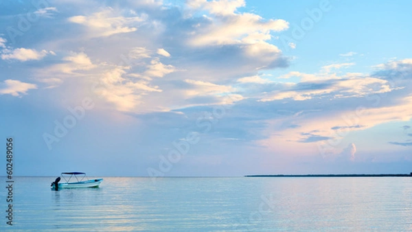 Obraz a fishing boat on the seashore of holbox, a beach in the riviera maya. a sky with many clouds painted in blue and pink. very relaxing landscape.
