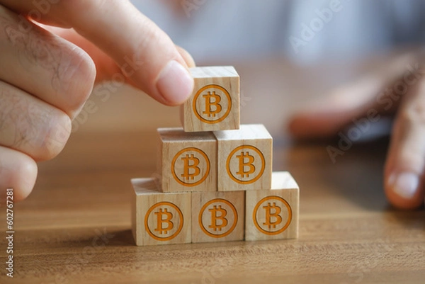 Obraz Businessman stacking wooden blocks on top of each other, wooden blocks have bitcoin symbols on them.