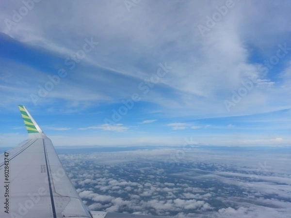 Fototapeta Airplane wing view from windows while flying in the air among the clouds and blue sky
