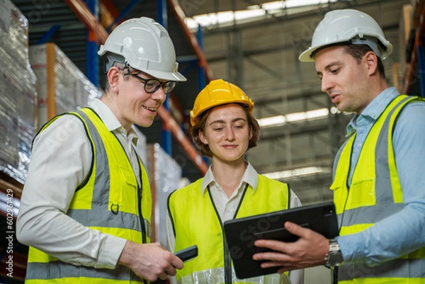 Fototapeta Warehouse employees reading a clipboard ann checking packages on shelf in a large logistics centre.