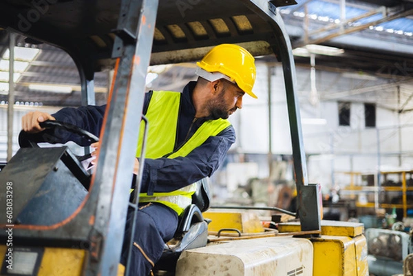 Obraz worker wearing helmet with driving forklift backwards in warehouse