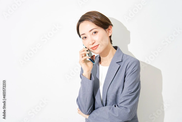 Fototapeta スマートフォンで電話するビジネスウーマン　白背景