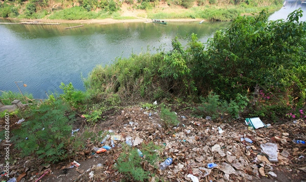 Fototapeta Rubbish, plastic bottles cans, paper by the Nam Khan / Mekong river in Luang Prabang.