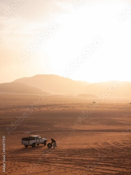 Fototapeta Beduin man changing the tire on his jeep in the Wadi Rum desert. 