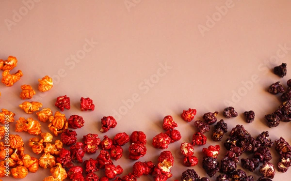 Fototapeta Multi-colored popcorn in caramel glaze scattered in rows on a pink background