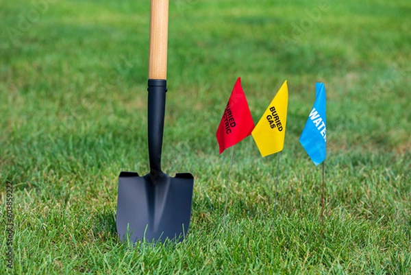 Fototapeta Buried electric, natural gas and water utility warning flag with shovel. Notify utility locate company for underground utilities, call before you dig and digging safety concept