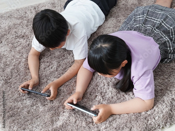 Obraz スマホに夢中の小学生の子供