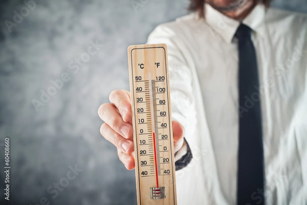 Fototapeta Businessman holding thermometer with temperature on Zero value