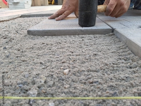 Fototapeta Rubber hammer when laying paving slabs. Laying paving slabs with a kiyanka. A sunny summer day.