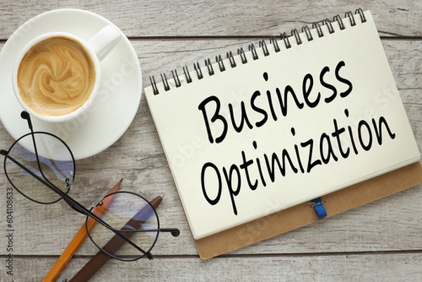 Fototapeta business optimization concept. On a wooden background, a notepad with text with a cup of coffee and glasses