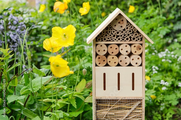 Fototapeta An insect hotel or bee hotel in a summer garden. An insect hotel is a manmade structure created to provide shelter for insects in a variety of shapes and sizes and materials.	