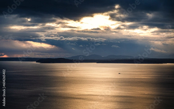 Obraz Dramatic sunlight through cloudy sky over sea surface, Seattle, USA.