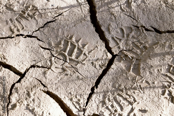 Fototapeta Footprints of human footsteps on broken and dry ground