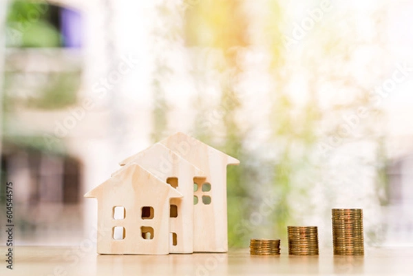 Obraz Wooden house model and stack gold coin of sunlight in the public park, Saving money or loan for business investment real estate or buy a new home for a family concept.