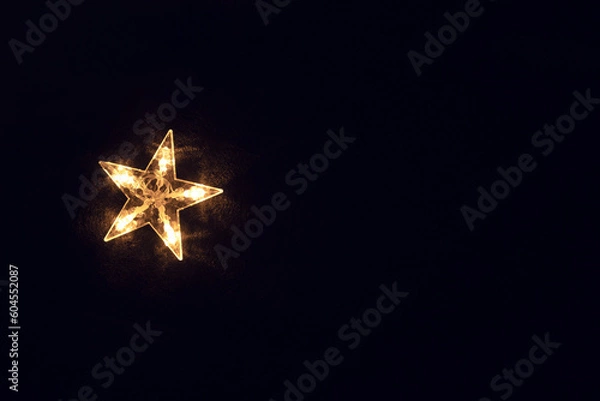 Obraz A bright glowing star on a black background. Black background with one five-pointed bright star.