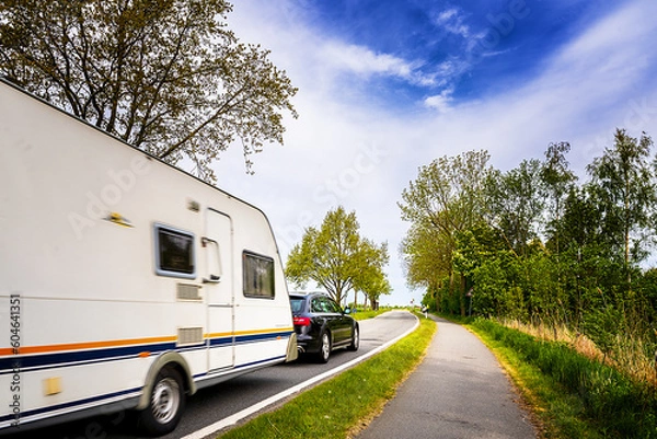 Obraz Auto mit Wohnwagen fährt auf einer Bundesstraße
