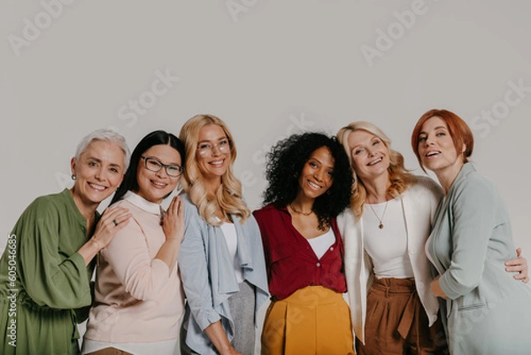 Fototapeta Multi-ethnic group of elegant mature women bonding and smiling against grey background