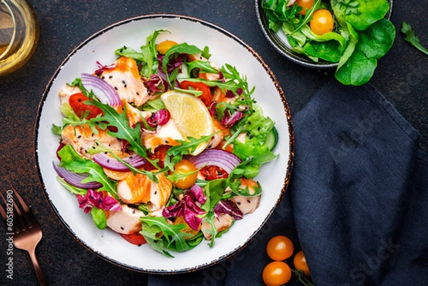 Obraz Gourmet salad with grilled salmon with tomatoes, cucumber, arugula, radicchio, red onion and lettuce with lemon oil dressing. Healthy lunch. Brown stone table background, top view