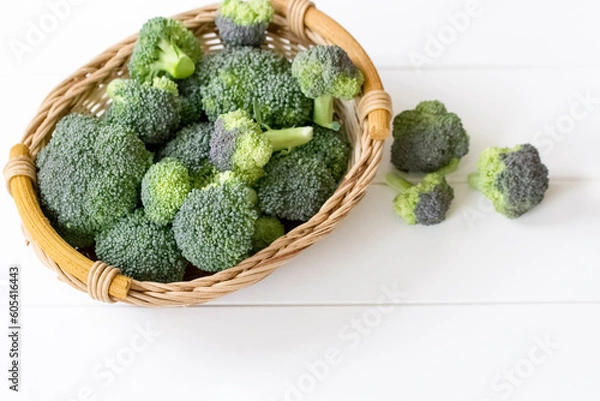 Fototapeta fresh broccoli in a wicker basket on a white background close-up. background with a broccoli harvest in a basket.