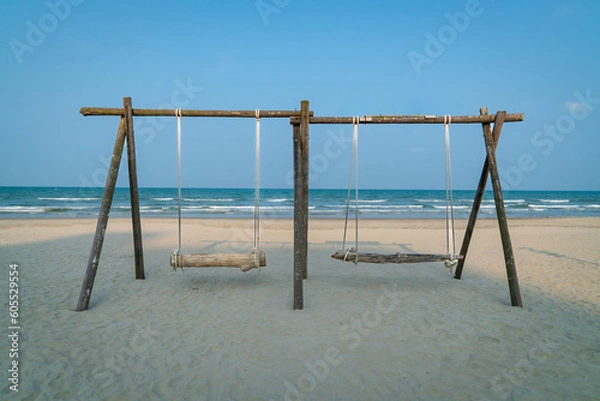 Fototapeta Swing made of wood and timber with two seats on the beach. Sea with horizon background. Travel or vacation concept.