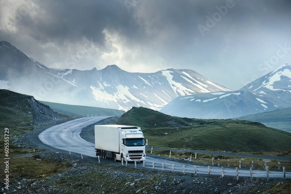 Fototapeta Large white transport truck transporting commercial cargo in semi trailer running on turning way highway road with scenic mountains mountaineous scenery in background.