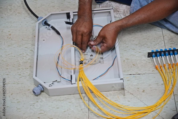 Fototapeta Technician installing fiber optic cable in junction box