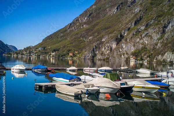 Fototapeta Lake Lugano surrounded by mountains and a small marina with moored boats on a sunny day