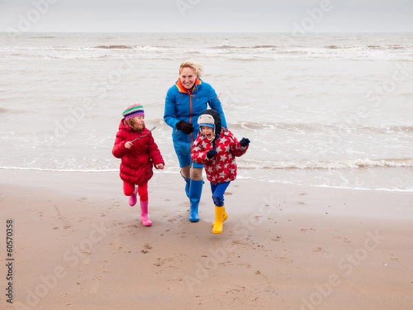 Fototapeta kobieta i dwoje małych dzieci bawiące się na plaży w zimie