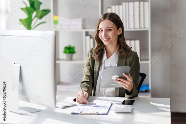 Fototapeta Concept of business office woman working,Businesswoman smile while working about her invesment plan with analyzing document and business investment graph data by using laptop on desk in workstation.