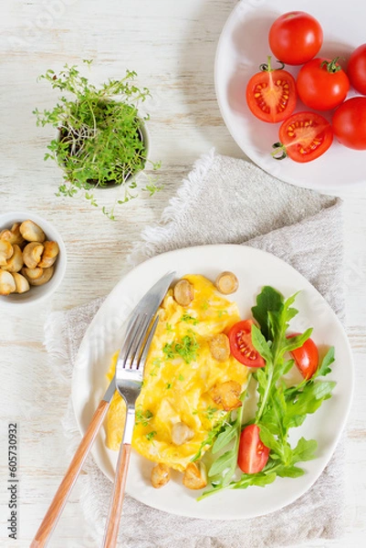 Obraz American scramble omelet top view with arugula, tomatoes and mushrooms, next to a plate with mushrooms and tomatoes