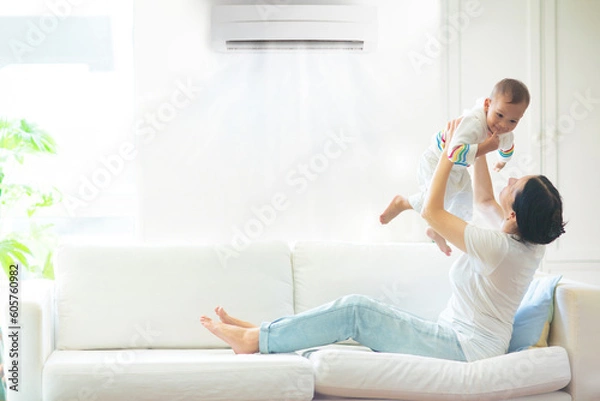 Obraz Mother and child with air conditioner remote