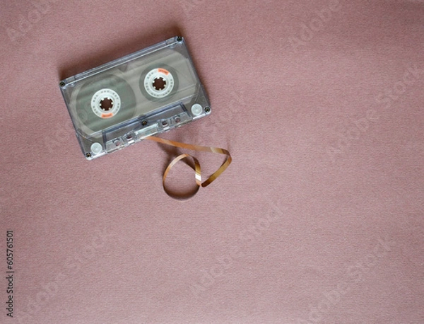 Fototapeta Audio cassette with tangled tape on a purple background, top view.