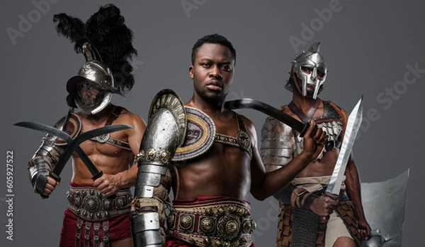 Fototapeta Portrait of handsome african gladiator from past with paired swords and two comrades.