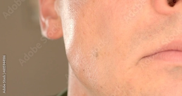 Fototapeta The movement of the muscles of the cheekbones of a man on the cheek. Tension of the jaw, tone of the jaw joint. Demonstration of aggression and dominance of a man. Close-up.