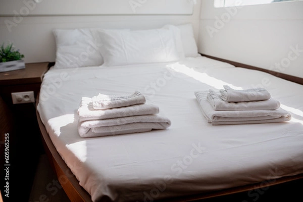 Fototapeta Interior of bedroom in cabin of catamaran with comfortable bed with white bedclothes